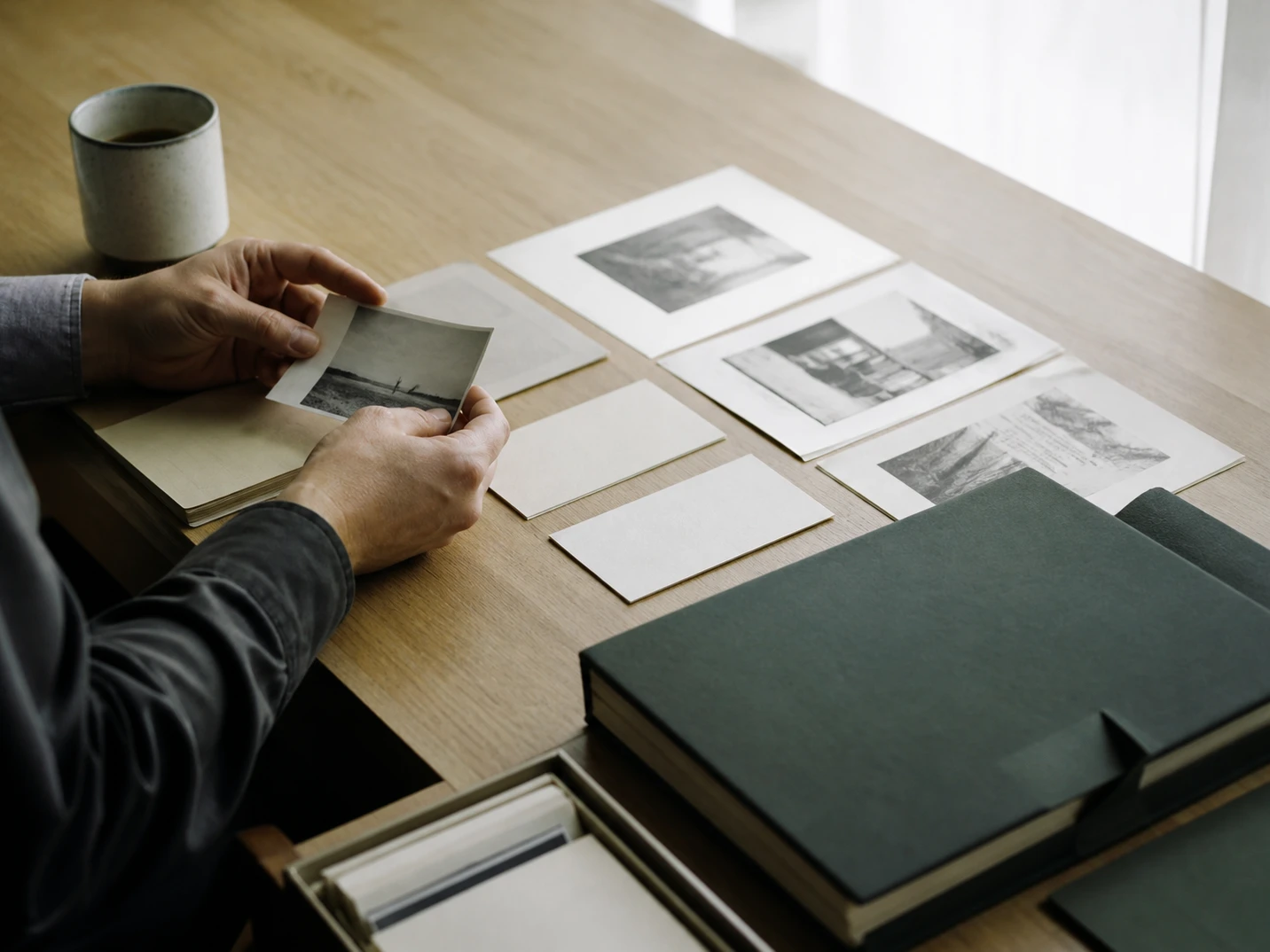 Printed sources and index cards arranged for review on a pale-wood desk